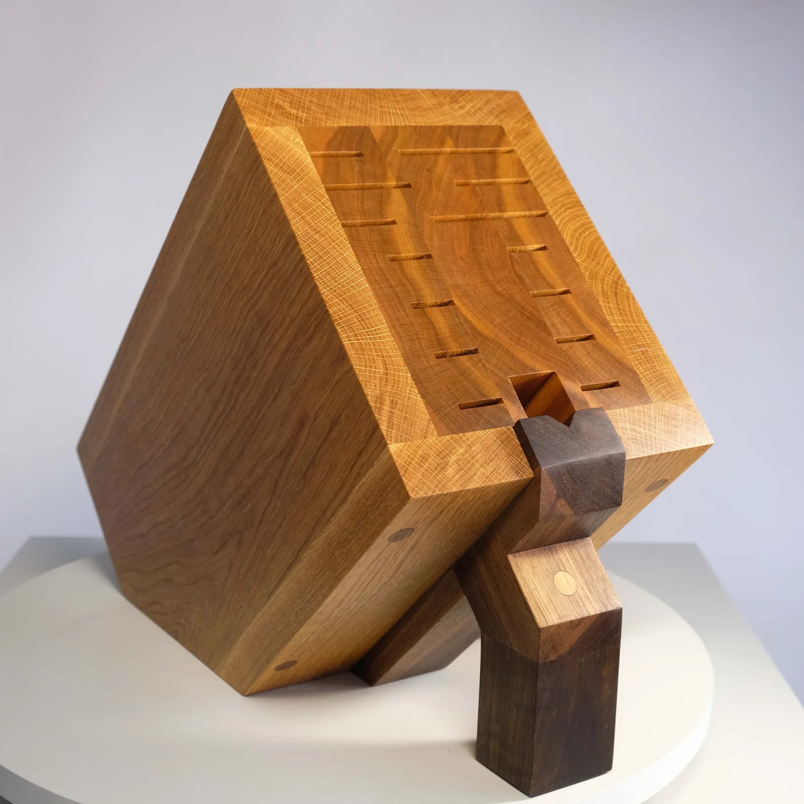 Angled knife block in light wood on a dark stand