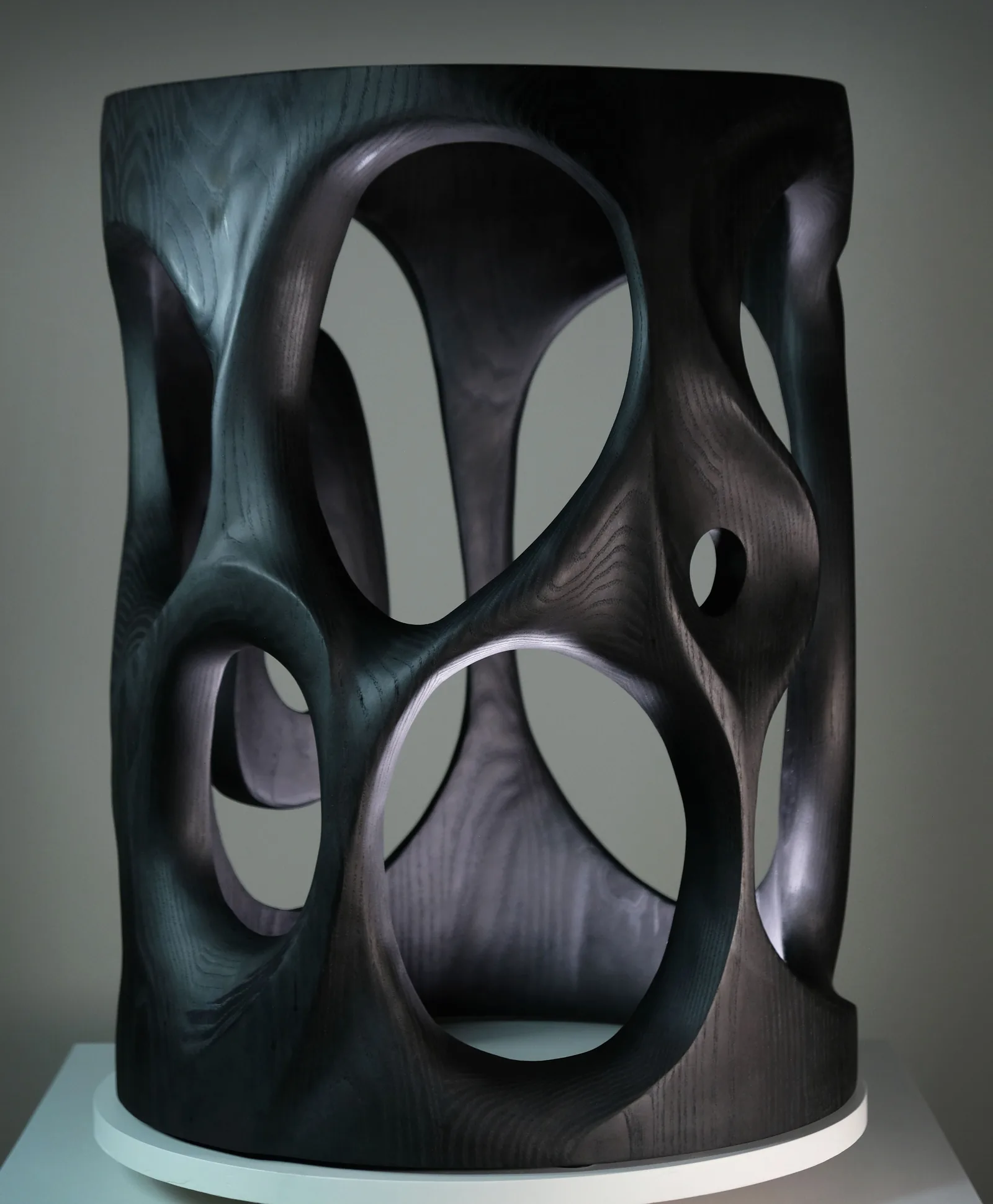Sculpted side table in blackened ash with open carved shapes