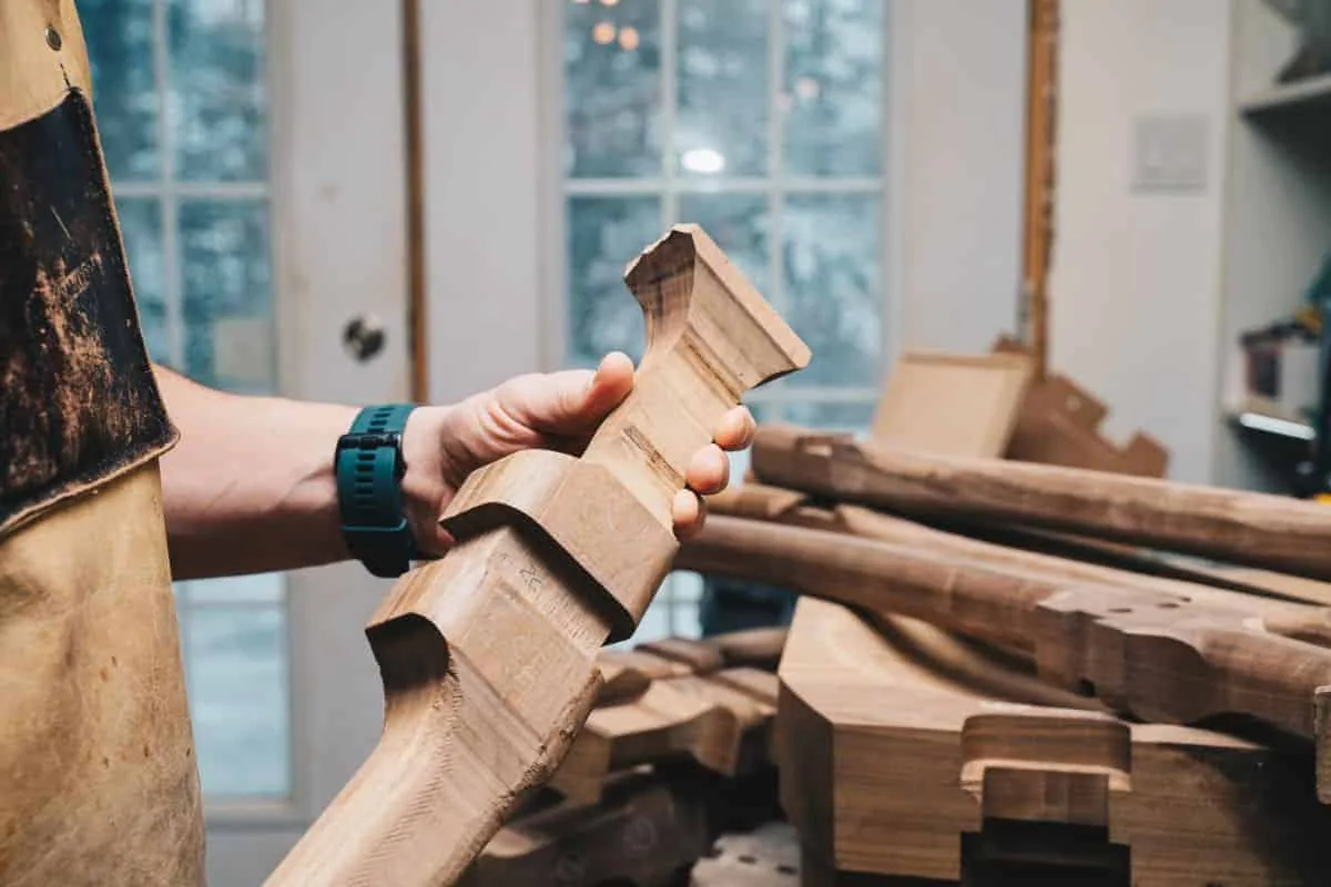 Close view of a hand holding a carved hardwood leg in the studio