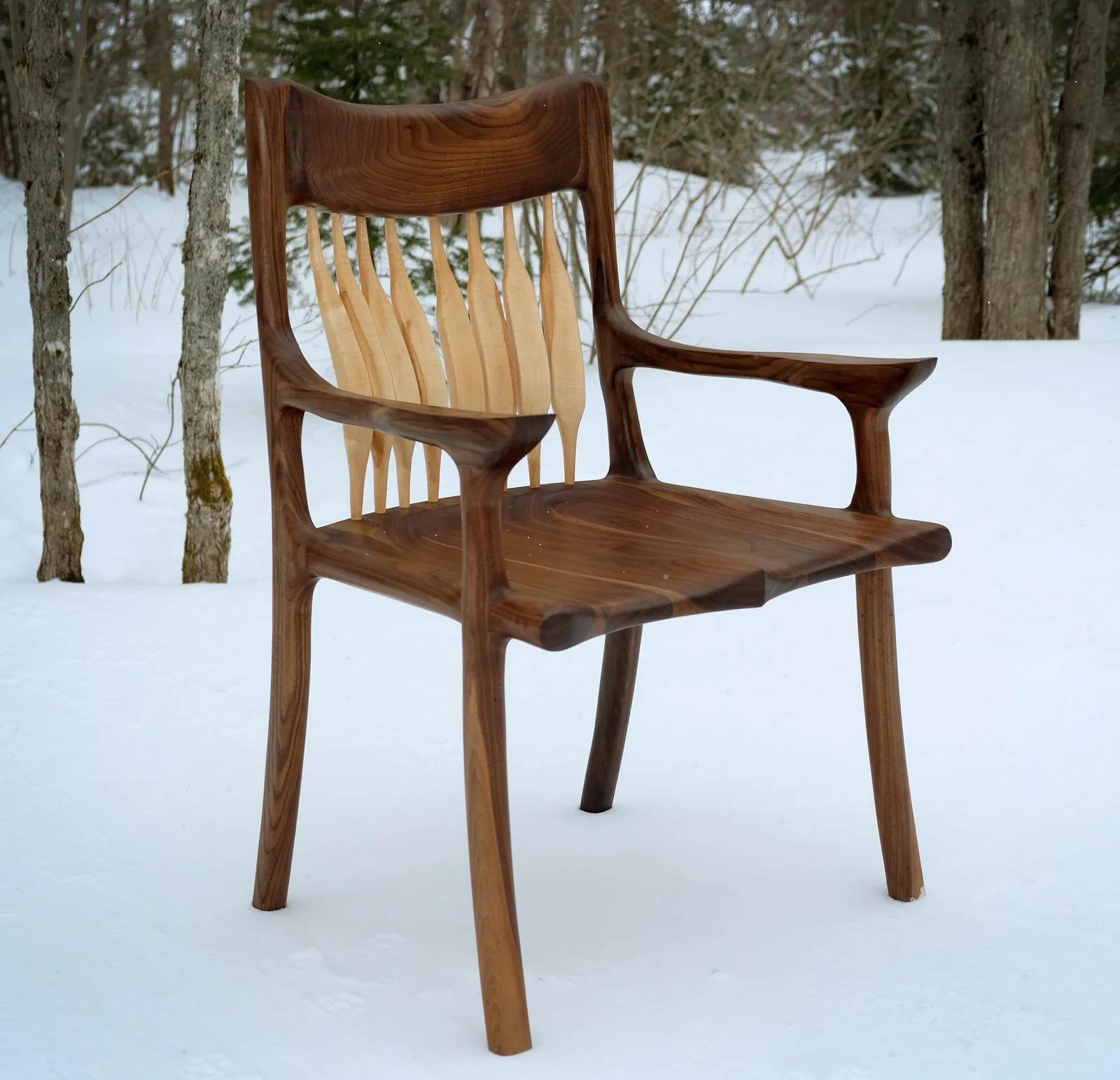 Walnut dining chair with a shaped backrest, photographed outdoors in snow