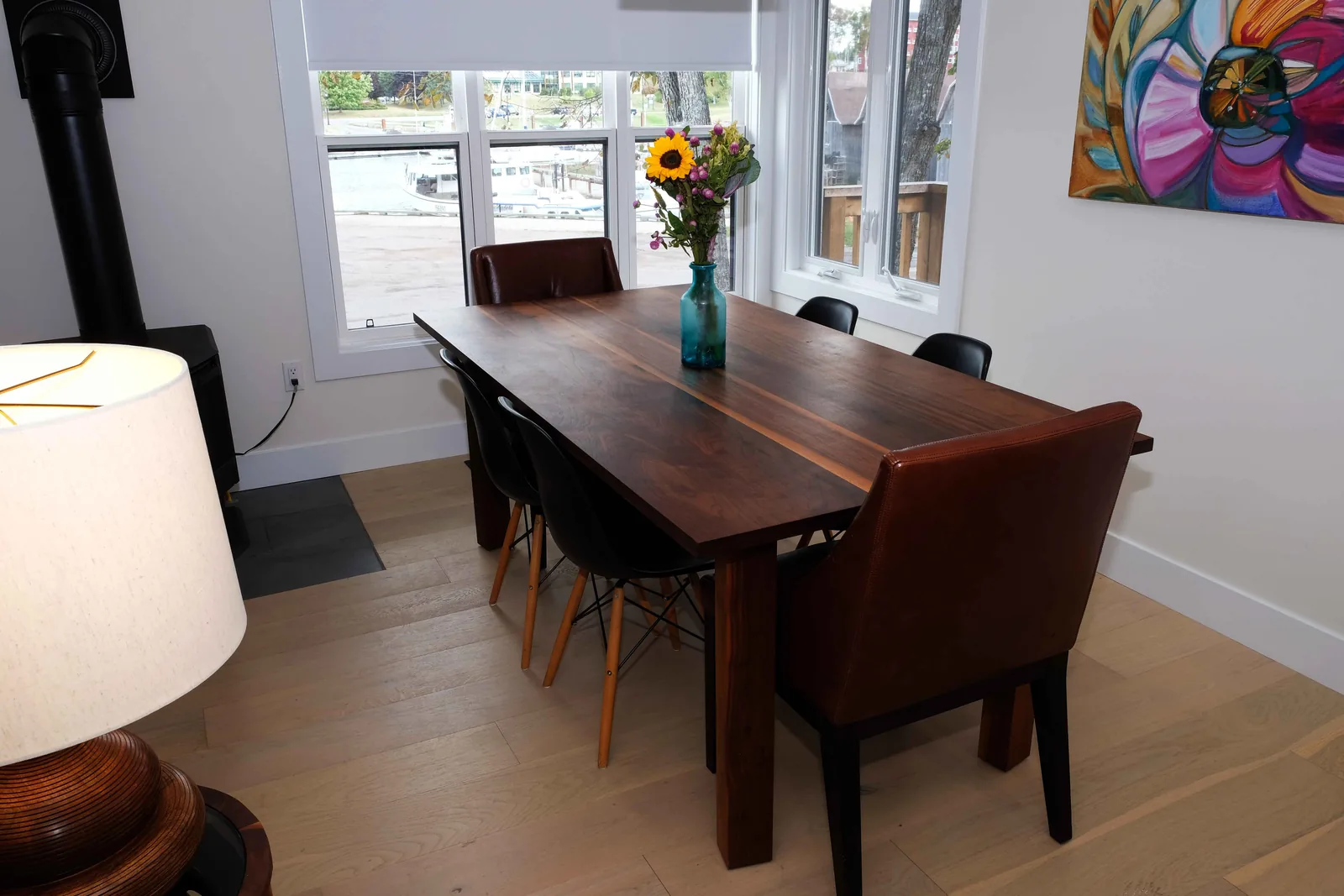 Walnut dining table with black and leather chairs in a bright dining room