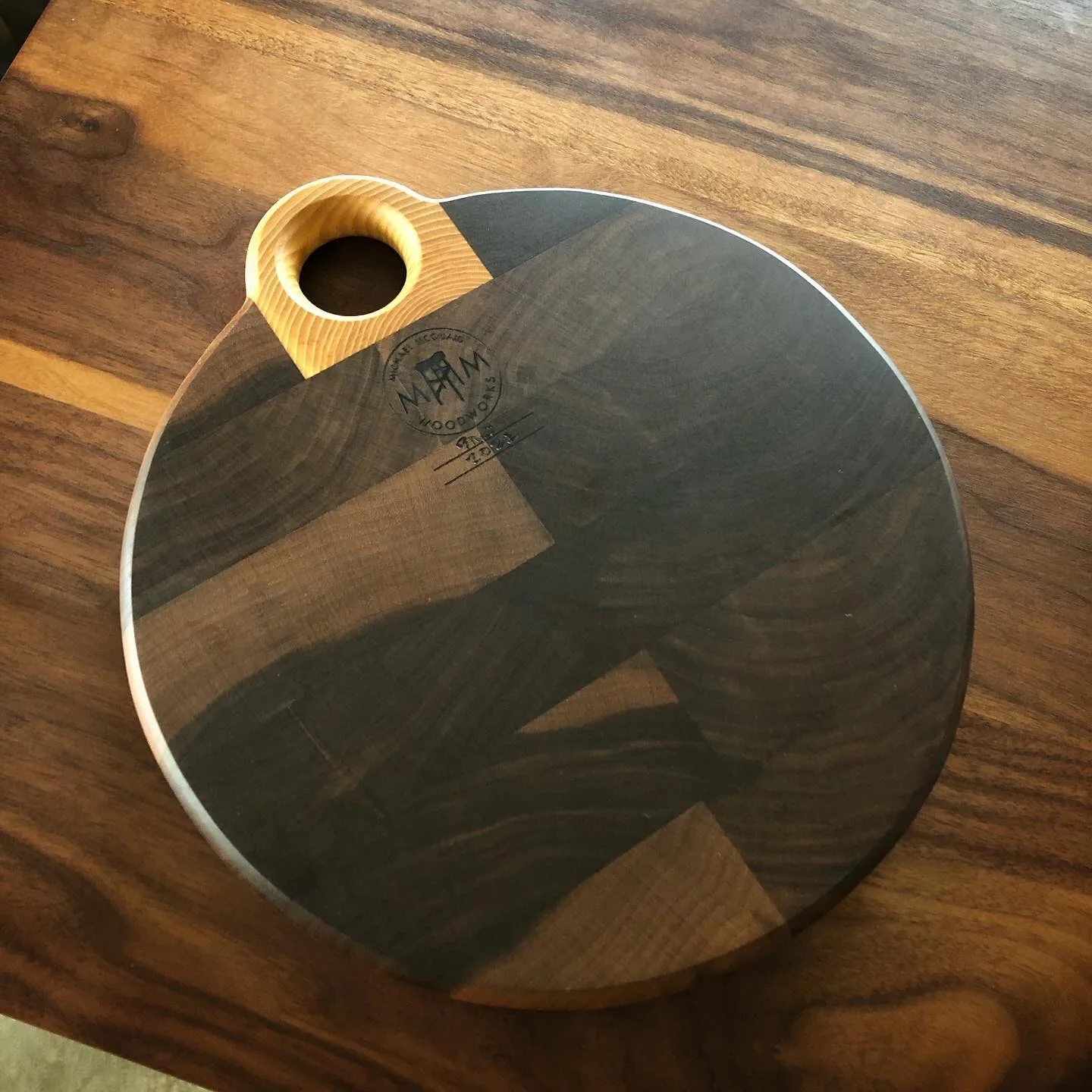 Round dark walnut board with a light ash handle