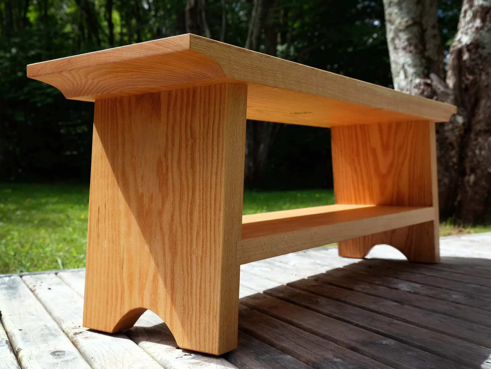 White oak bench with a low shelf on a deck